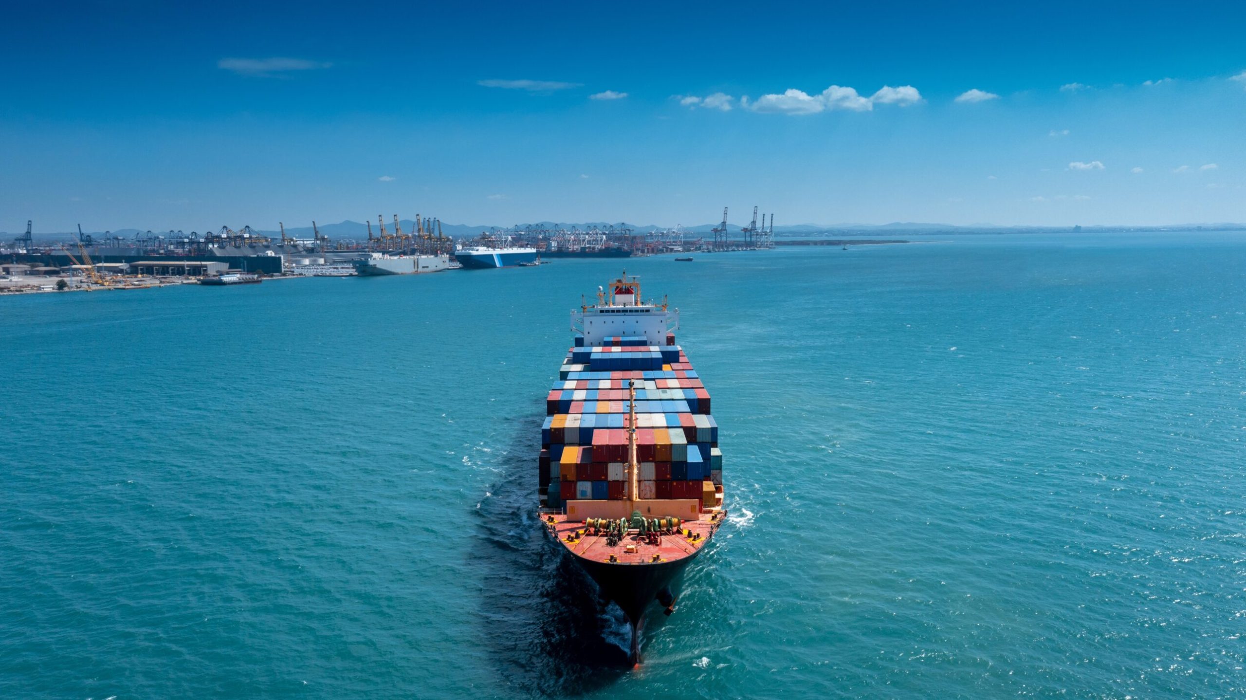 Aerial in front of cargo ship carrying container and running for export  goods  from  cargo yard port to custom ocean concept freight shipping by ship .