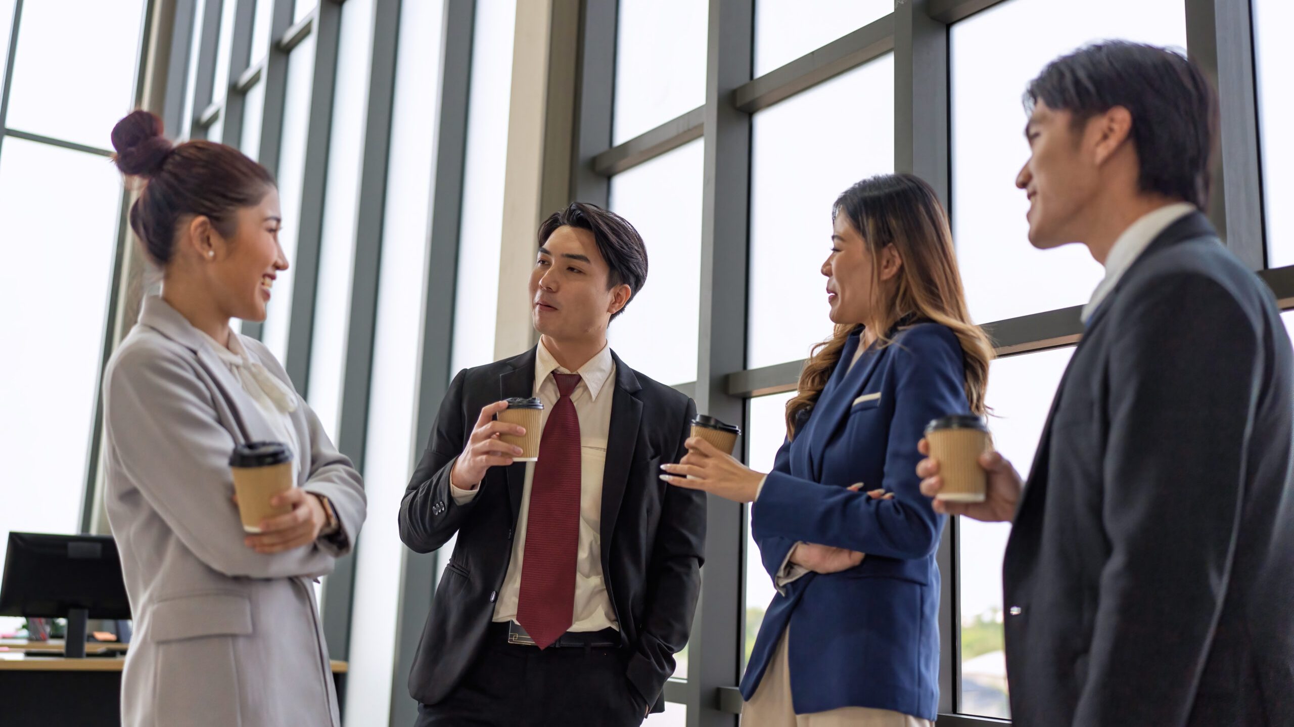 Business meeting of business people in office formal wear stand hold glass of coffee on break time